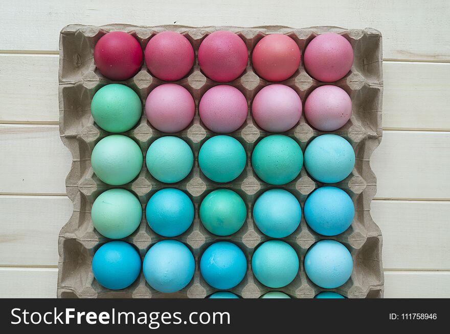 Easter.Pastel colored eggs.Spring composition.Flat ley.Many Easter eggs lie in a container for eggs. Curly eggs.Handmade.Wooden background. Basket woven