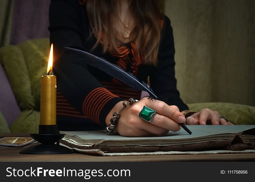 Tarot cards on fortune teller desk table. Future reading. Woman witch writes a magic scroll book with feather pen. Author. Tarot cards on fortune teller desk table. Future reading. Woman witch writes a magic scroll book with feather pen. Author.