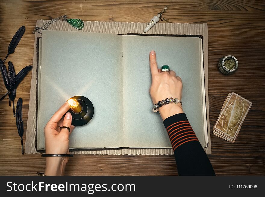 Book of magic. Tarot cards on fortune teller desk table. Future reading. Woman witch reads a ancient magic scroll book with copy space and blank pages and learn art of prediction on wooden table. Book of magic. Tarot cards on fortune teller desk table. Future reading. Woman witch reads a ancient magic scroll book with copy space and blank pages and learn art of prediction on wooden table.