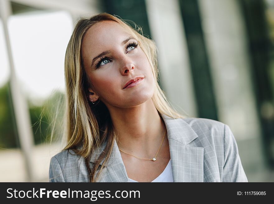 Blond girl wearing casual clothes in the street. Female with blue eyes. Beautiful young caucasian woman in urban background. Blond girl wearing casual clothes in the street. Female with blue eyes. Beautiful young caucasian woman in urban background.