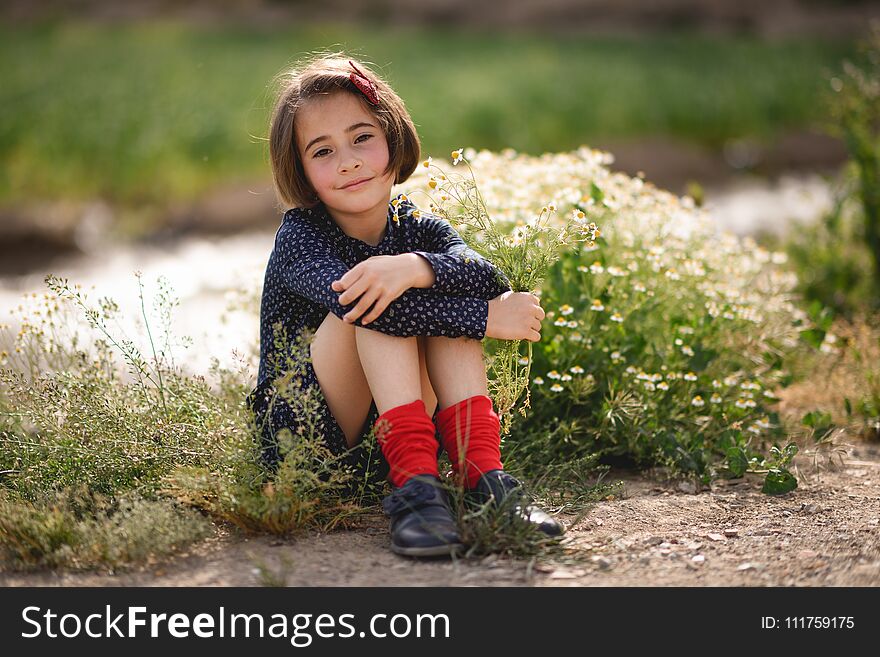 Little Girl Sitting In Nature Field Wearing Beautiful Dress