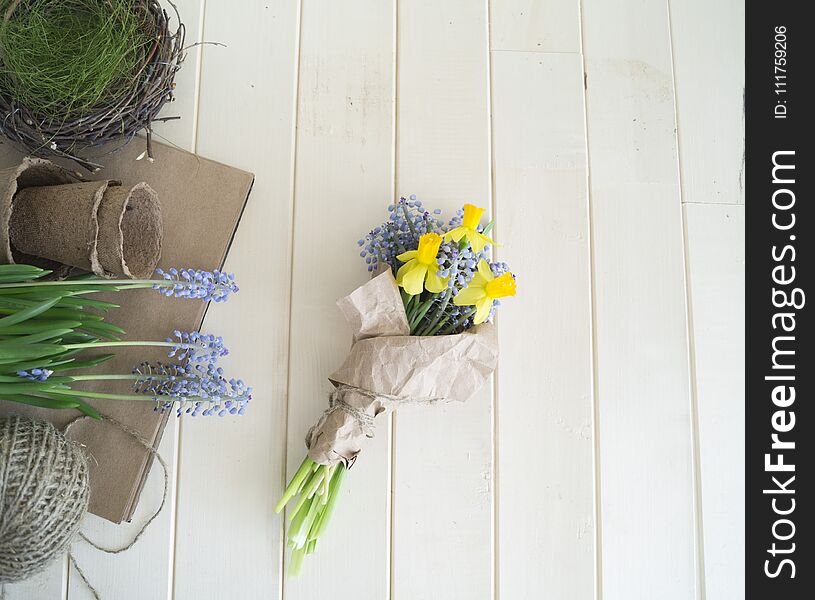 Children`s hands collect a bouquet as a gift. A gift for mom. Spring festive bouquet in a crafting package. Pruning flowers. The child is a florist. Wooden background. Field bouquet. Eco-style.