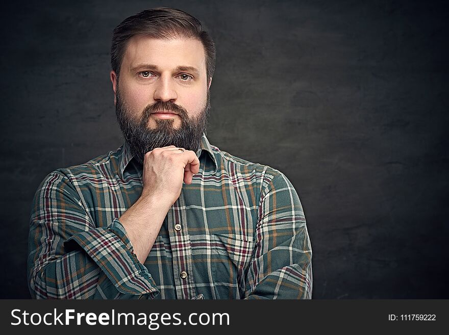Portrait of serious middle age bearded male dressed in plaid flannel shirt over grey background. Portrait of serious middle age bearded male dressed in plaid flannel shirt over grey background.