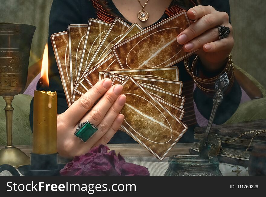 Tarot cards on fortune teller desk table. Future reading. Woman fortune teller holding in hands a deck of tarot cards. Tarot cards on fortune teller desk table. Future reading. Woman fortune teller holding in hands a deck of tarot cards.