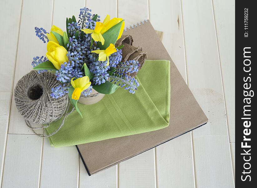 Bouquet of daffodils, tulips and Muscari.Easter. Easter eggs are blue and turquoise.The bird`s nest. Wooden background. The style of eco.Green,brown,blue, lilac and yellow.