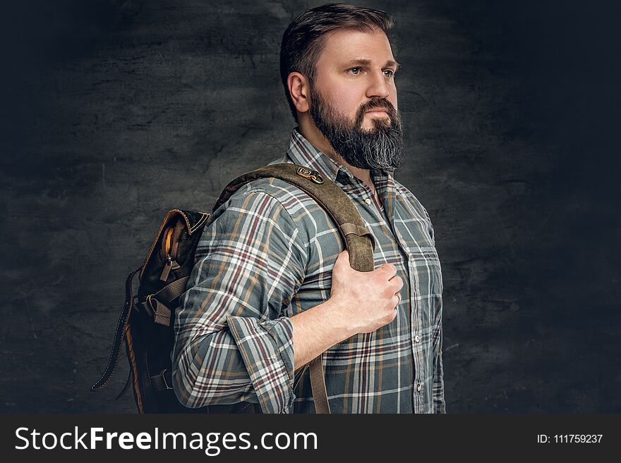Portrait of bearded male dressed in a fleece shirt holds backpack on his shoulder. Portrait of bearded male dressed in a fleece shirt holds backpack on his shoulder.