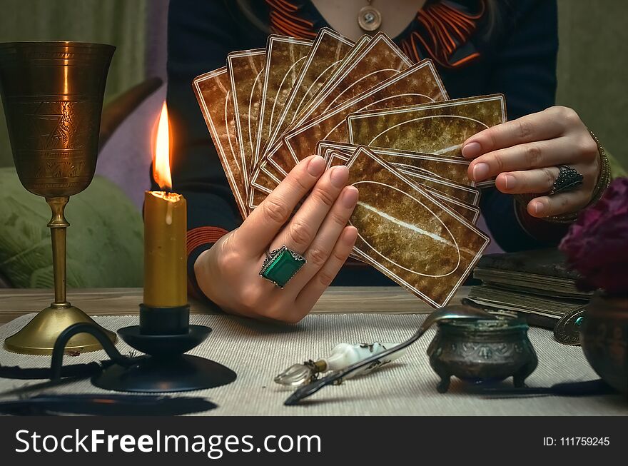 Tarot cards on fortune teller desk table. Future reading. Woman fortune teller holding in hands a deck of tarot cards. Tarot cards on fortune teller desk table. Future reading. Woman fortune teller holding in hands a deck of tarot cards.