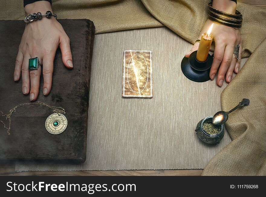 Book of magic. Tarot cards on fortune teller desk table. Future reading. Woman witch reads a ancient magic scroll book and learn art of prediction on wooden table. Book of magic. Tarot cards on fortune teller desk table. Future reading. Woman witch reads a ancient magic scroll book and learn art of prediction on wooden table.