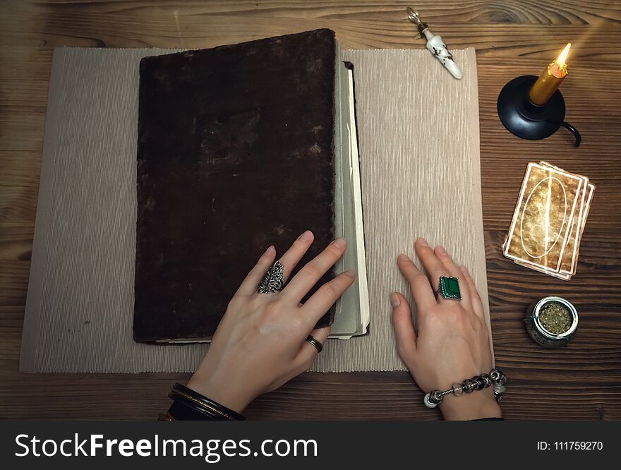 Book of magic with mystical light. Tarot cards on fortune teller desk table. Future reading. Woman witch open ancient magic scroll book and learn art of prediction on wooden table. Book of magic with mystical light. Tarot cards on fortune teller desk table. Future reading. Woman witch open ancient magic scroll book and learn art of prediction on wooden table.