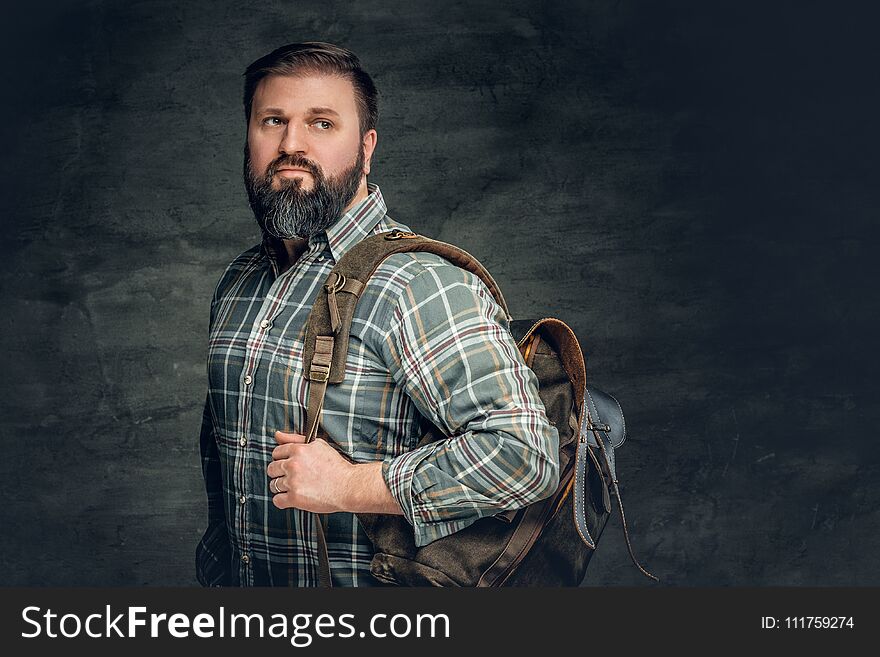 Portrait of bearded male dressed in a fleece shirt holds backpack on his shoulder. Portrait of bearded male dressed in a fleece shirt holds backpack on his shoulder.