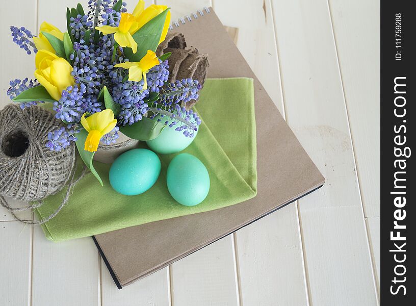 Bouquet of daffodils, tulips and Muscari.Easter. Easter eggs are blue and turquoise.The bird`s nest. Wooden background. The style of eco.Green,brown,blue, lilac and yellow.