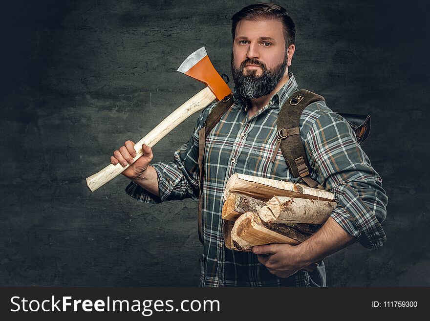 Portrait of brutal bearded hunter male holds an axe on his shoulder.