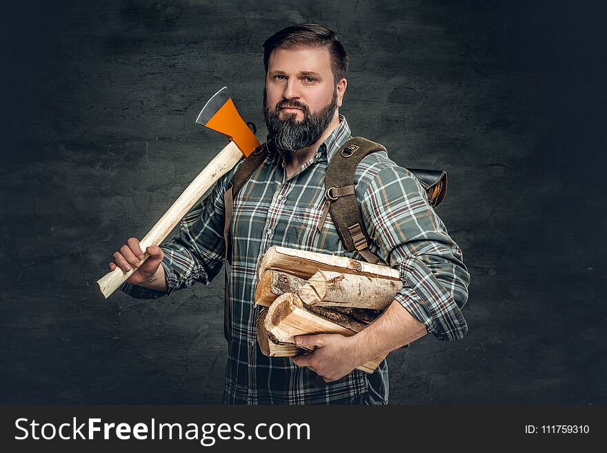 Portrait of brutal bearded hunter male holds an axe on his shoulder.