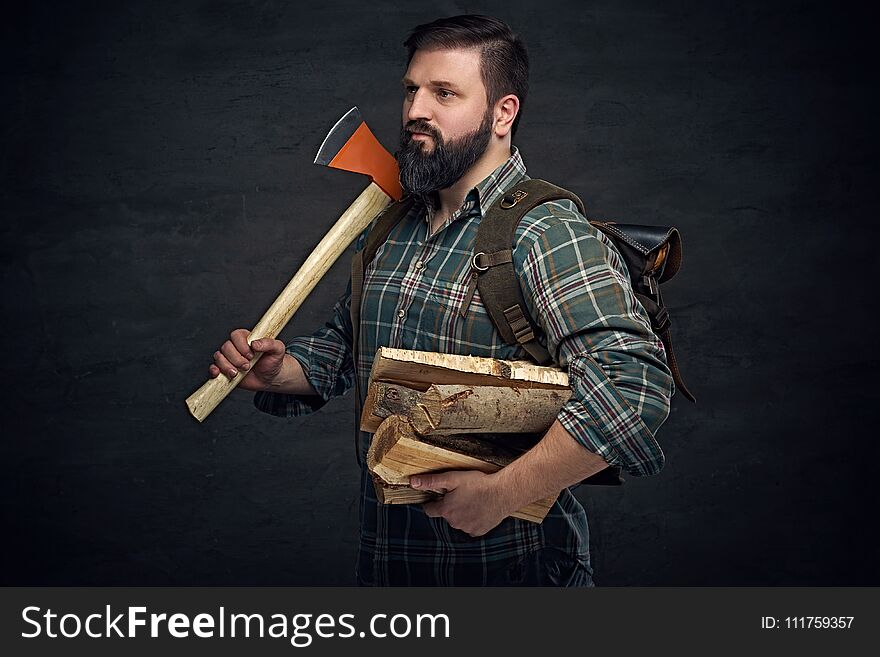 Bearded middle age male holds an axe and firewoods.