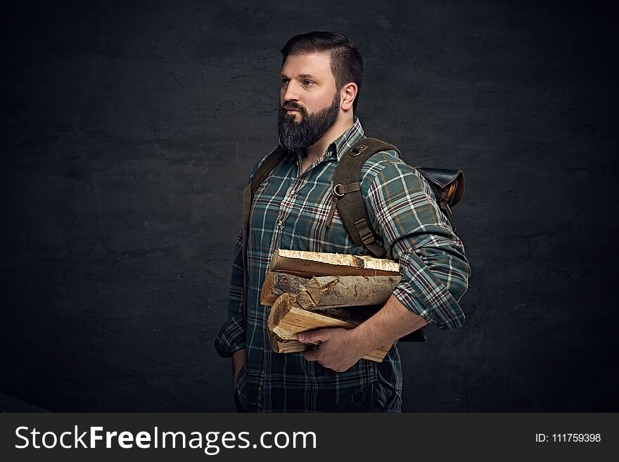 Middle age male holds backpack and firewoods.