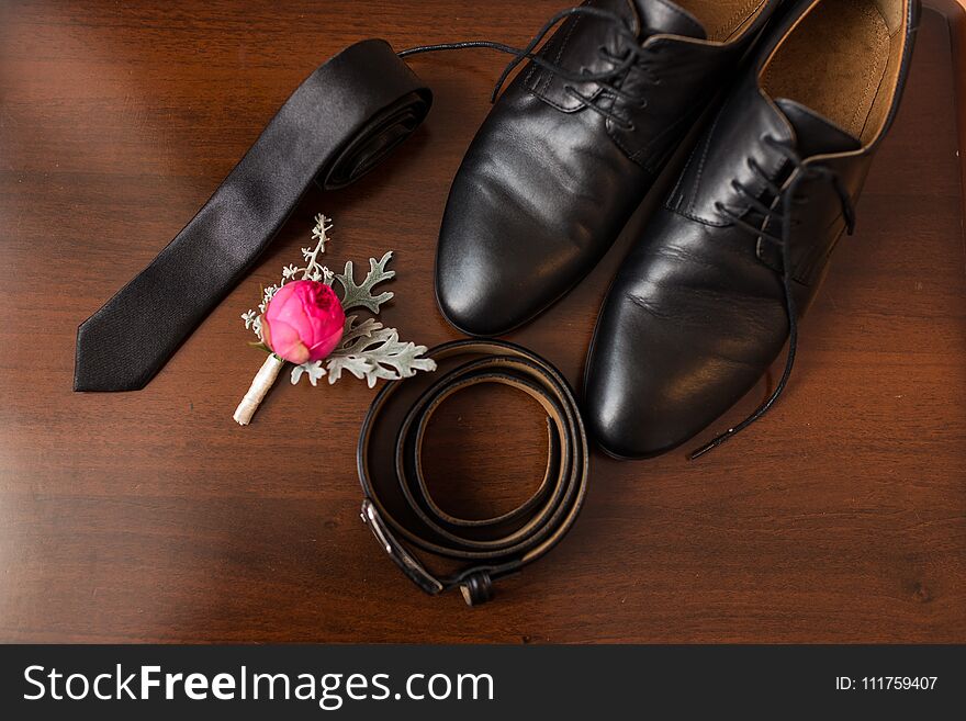 Groomâ€™s accessories: flower boutonniere, leather belt, necktie, shoes. Wedding