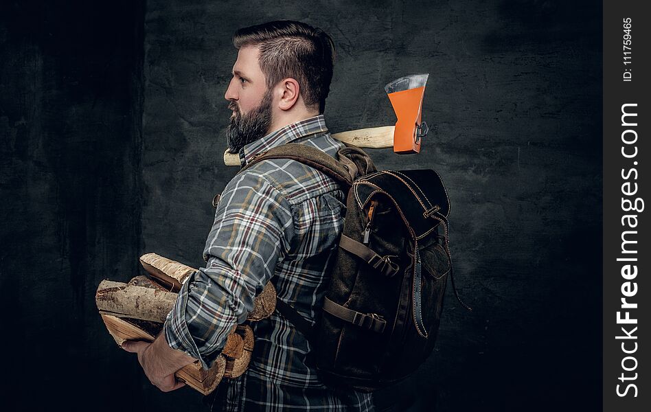 Portrait of brutal bearded hunter male holds an axe on his shoulder.