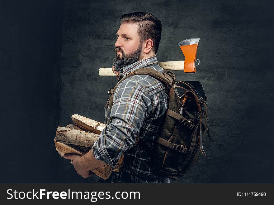 Portrait of brutal bearded hunter male holds an axe on his shoulder.