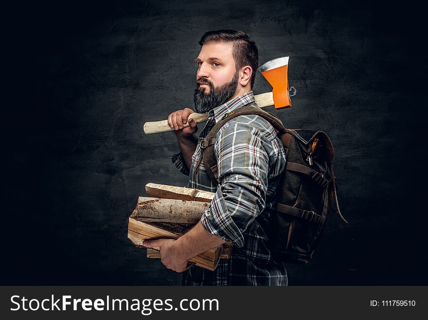 Portrait of brutal bearded hunter male holds an axe on his shoulder.