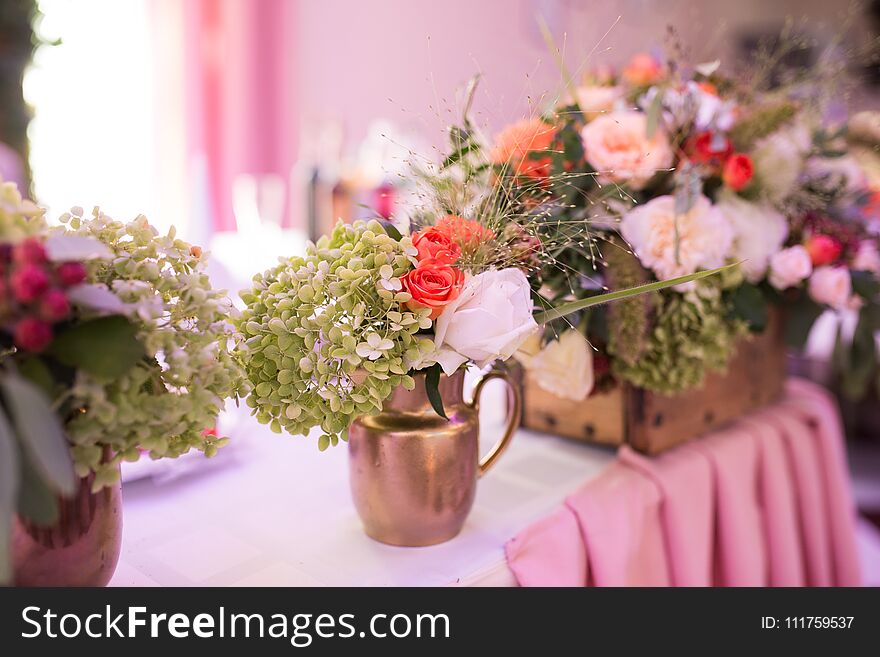 Rustic flower arrangement in a golden vase at a wedding banquet. Table set for an event party or wedding reception.