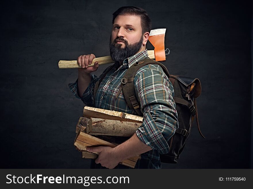 Bearded middle age male holds an axe and firewoods.