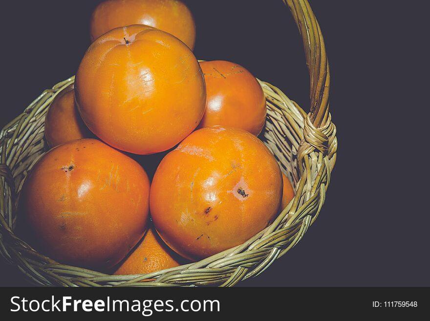 Delicious ripe persimmon, juicy orange fruits on black background, filtered. Delicious ripe persimmon, juicy orange fruits on black background, filtered.