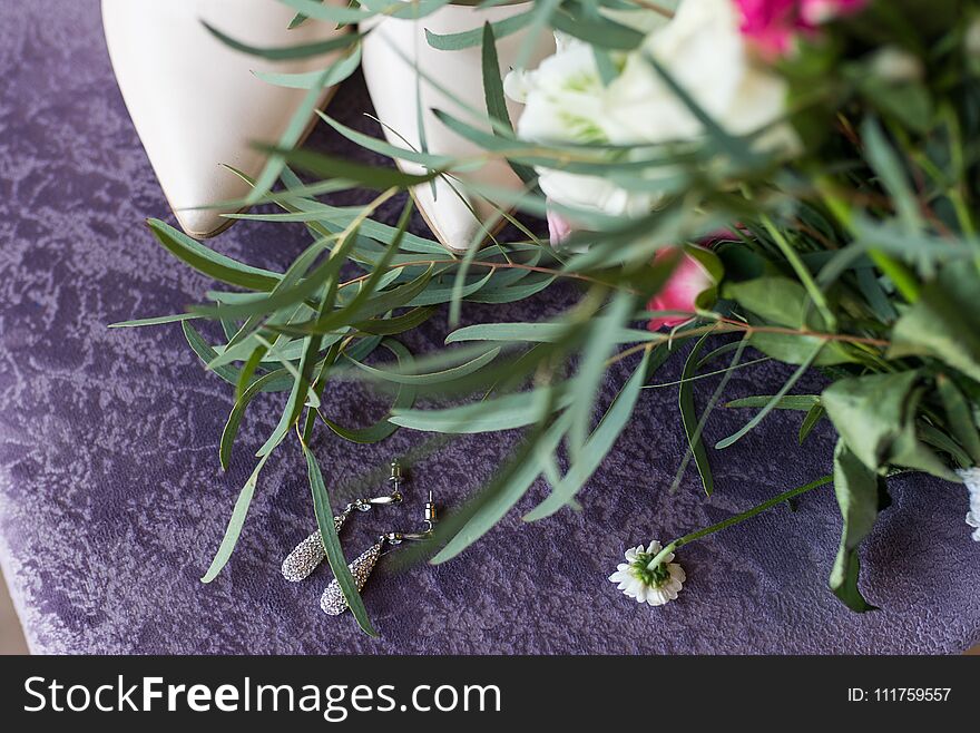 Wedding beige shoes and a bridal earring with gemstones lying on the lilac background. Wedding .