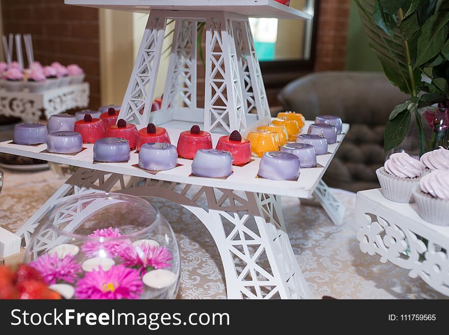 A Tray With Pink, Orange And Lilac Little Cakes. Candy Bar. A Lot Of Sweets At The Wedding Banquet.