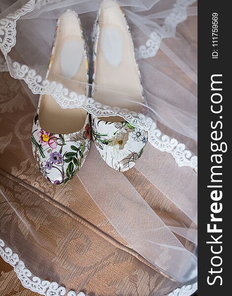 Shoes without heels with colorful flowers are covered with a veil. Wedding