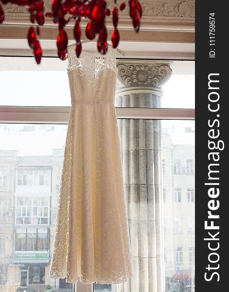 Wedding dress on hanger on a window. Beautiful gown. Wedding