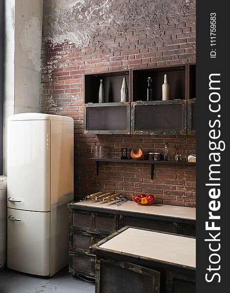 Part of the kitchen in loft style. White refrigerator on brick wall background. Loft