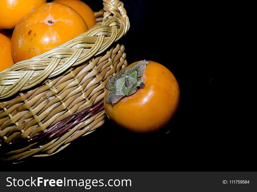 Delicious ripe persimmon, juicy orange fruits on black background. Delicious ripe persimmon, juicy orange fruits on black background.