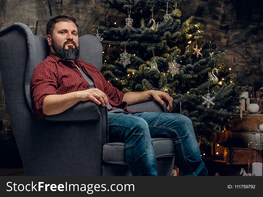 Bearded male over fir tree in background.