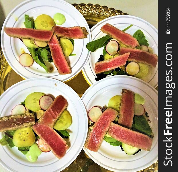 Seared raw tuna slices over pickled cucumbers, radish slices, and arugula. Seared raw tuna slices over pickled cucumbers, radish slices, and arugula