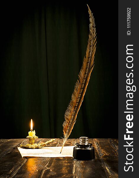 Education and writing concept, pen in ink bottle and candlestick with candle on wooden table on dark background. Education and writing concept, pen in ink bottle and candlestick with candle on wooden table on dark background.