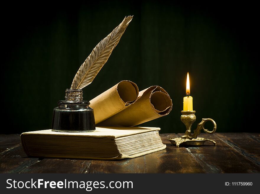 Education and writing concept, pen in ink bottle and candlestick with candle on wooden table on dark background. Education and writing concept, pen in ink bottle and candlestick with candle on wooden table on dark background.