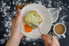 Mint Cake On A Plate With Tangerines In Hands. The Background Is A Dark Surface Sprinkled With Powdered Sugar, A Cup Of Coffee. Stock Photos