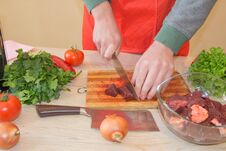 A Man In A Kitchen Apron, Meat On A Board And A Wooden Table, A Knife And Vegetables Royalty Free Stock Photos A Man In A Kitchen Apron, Meat On A Board And A Wooden Table, A Knife And Vegetables Royalty Free Stock Photos