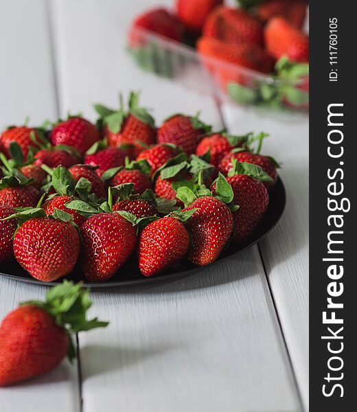 Lots of strawberries in a still life on a white background, summer garden wooden white table