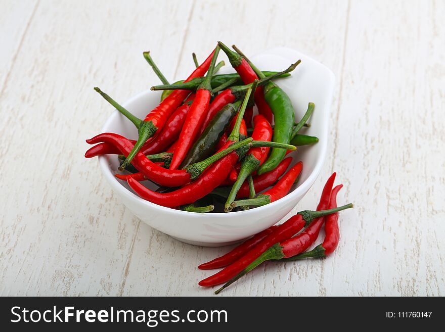 Hot chili pepper heap on the wood background