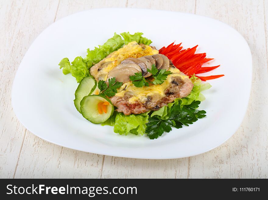 Pork steak with mushroom and cheese served salad leaves and cucumber