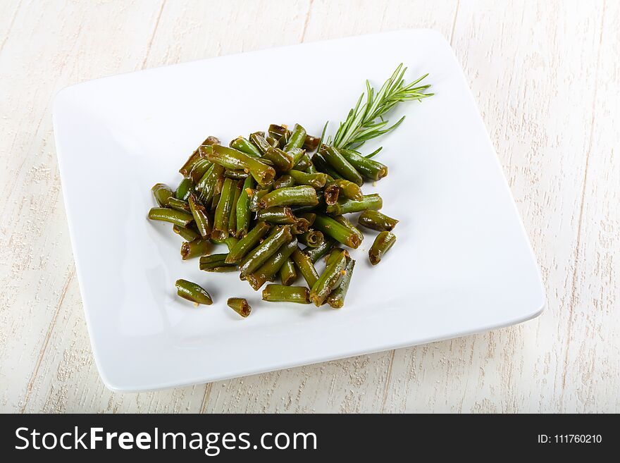 Baked green beans with rosemary on wood background