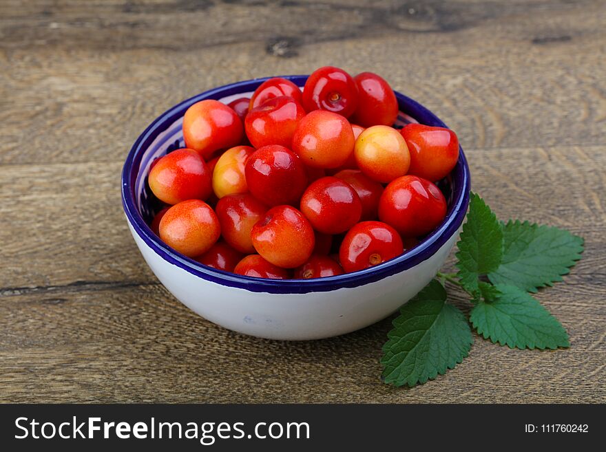 Sweet cherry in the bowl on wood background