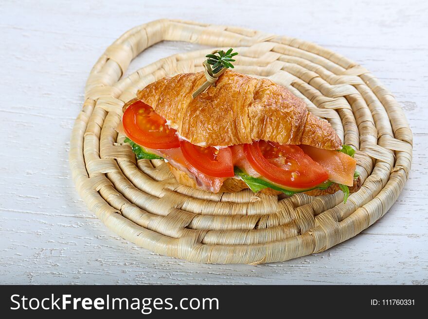 Croissant with salmon served rosemary on wood background