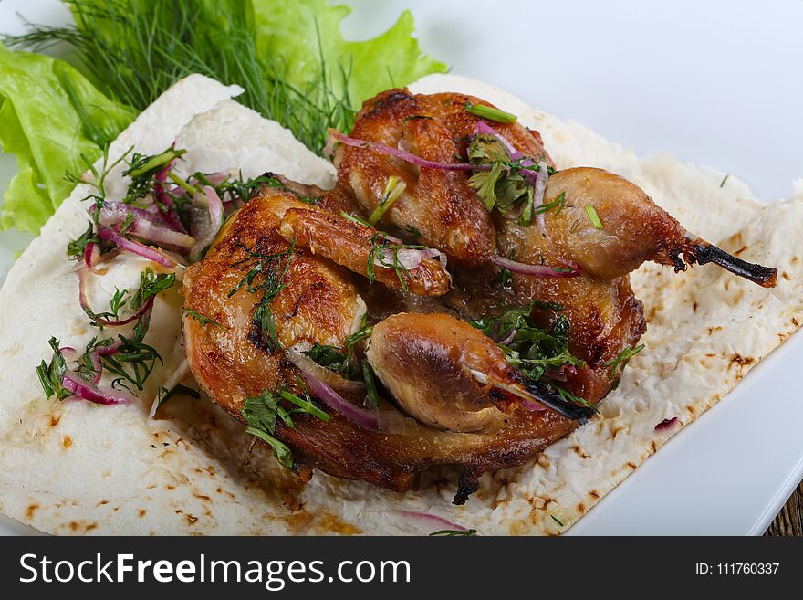 Grilled quail with onion and salad leaves