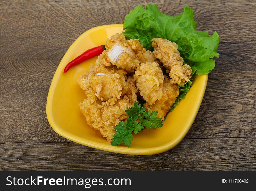 Crispy chicken nuggets with spices on wood background
