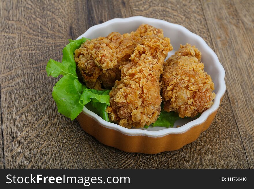 Crispy chicken wings with salad leaves on wood background