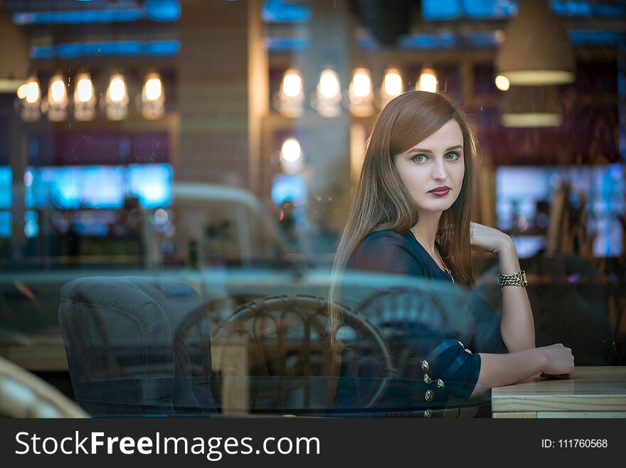 Pretty girl sitting at table and looking out window in cafe. Pretty girl sitting at table and looking out window in cafe