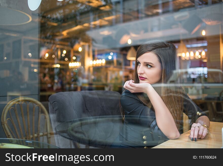 Pretty girl sitting at table and looking out window in cafe. Pretty girl sitting at table and looking out window in cafe