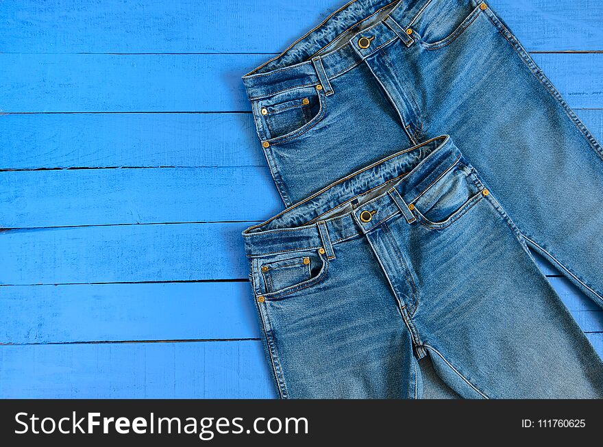 Womens clothing blue jeans on blue wooden background with copy space. Fashion outfit. Shopping concept. Top view